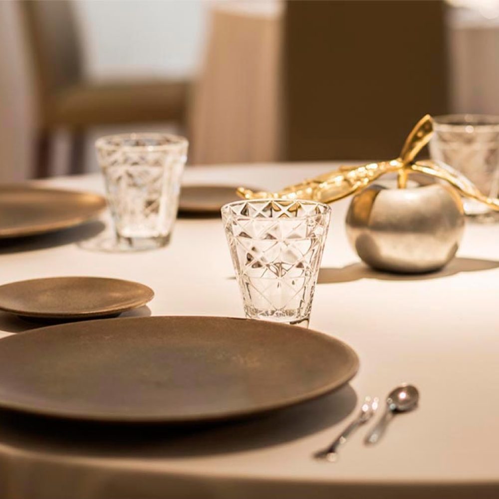 Detalle de una elegante mesa del Restaurante Massana preparada para ofrecer una experiencia gastronómica exclusiva, con una cuidada puesta en escena y una atmósfera cálida y sofisticada.